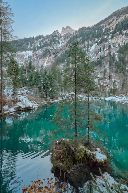 Małe jezioro o turkusowych wodach w śnieżnym otoczeniu znanym jako jezioro Blausee w Szwajcarii