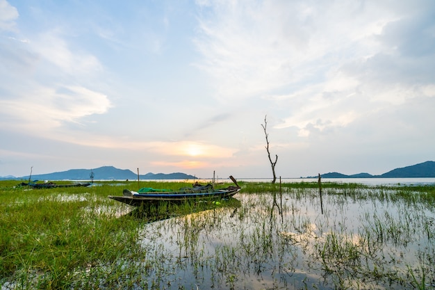 Małe łodzie rybackie zaparkowane na brzegu rzeki Bang Phra Reservoir wieczorem.