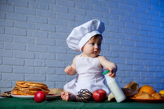 Małe piękne dziecko ubrane w fartuch, dziecięcy kostium kuchenny