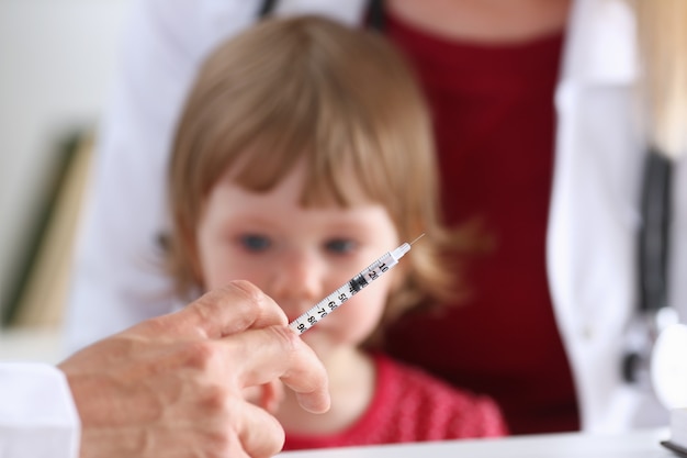 Małe przestraszone dziecko w recepcji lekarza robi zastrzyk insuliny