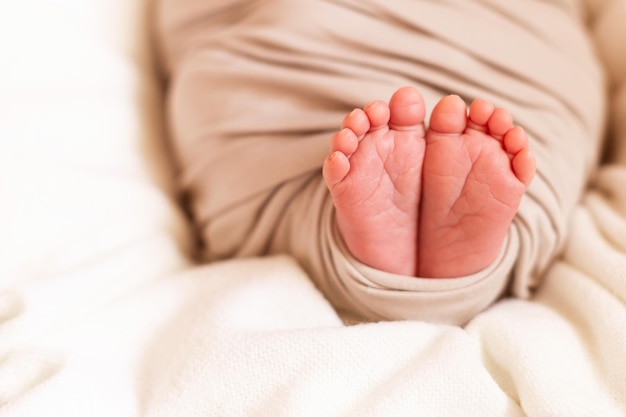 Małe stopy dziecka zbliżenie. Chusta dla niemowląt. Śpiące noworodka w koszu.