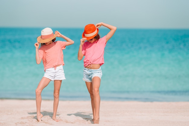 Małe szczęśliwe śmieszne dziewczyny bawią się razem na tropikalnej plaży.