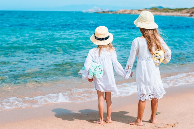 Małe szczęśliwe śmieszne dziewczyny bawią się razem na tropikalnej plaży.