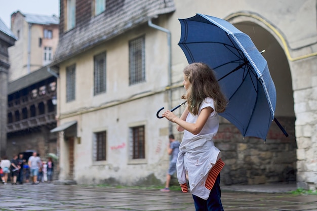 Małej dziewczynki dziecko w deszczu z parasolem, turystyczny stary miasto
