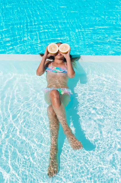 Małej dziewczynki nakrycie ono przygląda się z cytryn połówkami blisko oczu na pływackim basenie