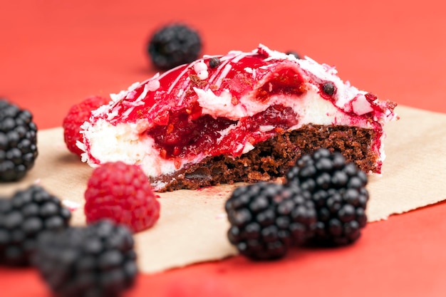 Zdjęcie maliny i jeżyny oraz czerwone ciasto z kremowym białym nadzieniem, czerwonym konfiturą