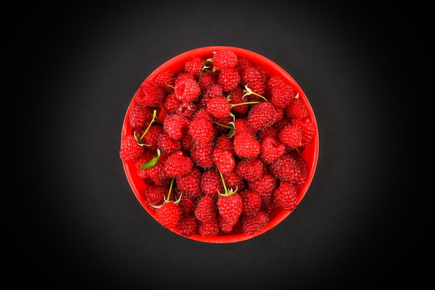 Maliny W Czerwonym Talerzu Na Czarnej Przestrzeni. Miska Ze świeżych Malin Na Różowym Obszarze. Skopiuj Miejsce. Minimalna Koncepcja. Ostre światło.