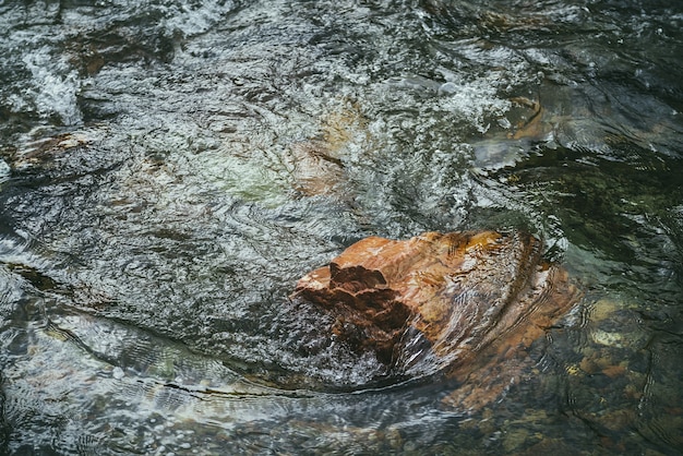 Malownicze Tło Natura Z żywym Pomarańczowym Kamieniem W Przezroczystej Wodzie Górskiej Rzeki. Kolorowe Kamieniste Dno Pod Czystą Wodą. Piękna Przyroda Tło Z Pomarańczowym Głazem W Górskiej Potoku.