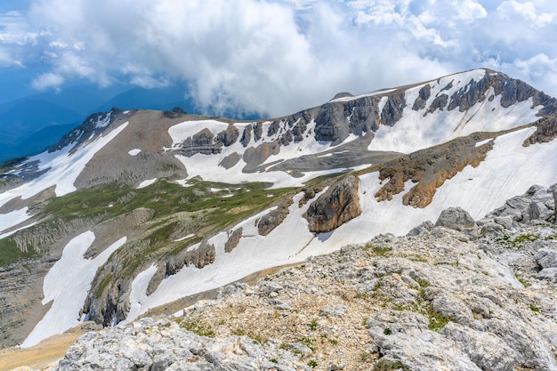 Malowniczy panoramiczny widok na idylliczny krajobraz wzgórz z kwitnącymi łąkami i ośnieżonymi szczytami alpejskimi