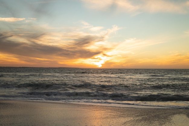 Malowniczy widok na fale na brzegu na plaży na tle nieba podczas zachodu słońca