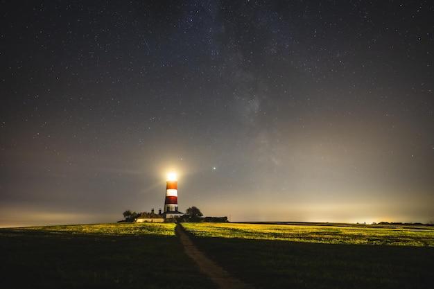 Malowniczy widok na latarnię morską Happisburgh oświetlającą w nocy, Wielka Brytania