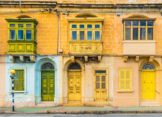 Malta, Valletta: Fasada domu mieszkalnego z tradycyjnymi maltańskimi balkonami. Dom z żółtej cegły na ulicy Maltańskiej.