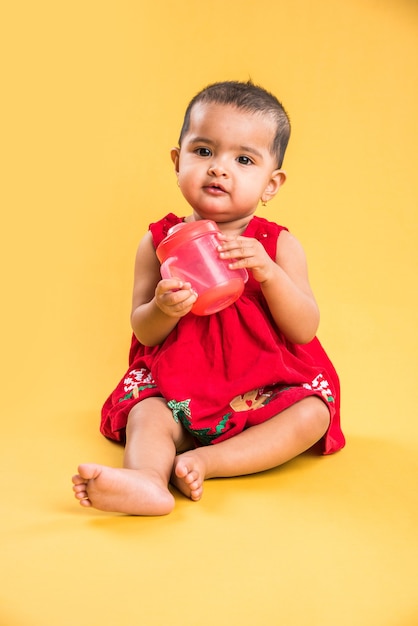 Maluch indyjski lub azjatycki, niemowlę lub dziecko bawiące się zabawkami lub klockami, leżąc lub siedząc na białym tle na jasnym lub kolorowym tle
