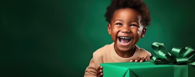 Mały afrykański chłopiec rozpakowuje prezent i śmieje się na zielonym tle Banner copy space Generative ai