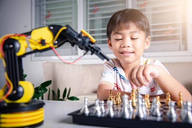Mały azjatycki chłopiec gra w szachy z ramieniem robota