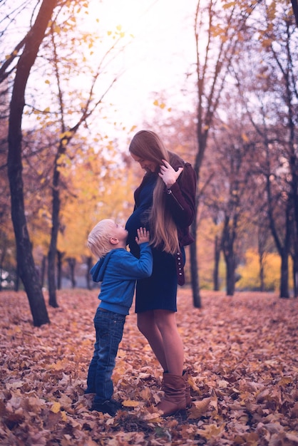 Mały Blond Chłopiec Przytula Brzuch Swojej Ciężarnej Mamy Jesienny Park W Tle