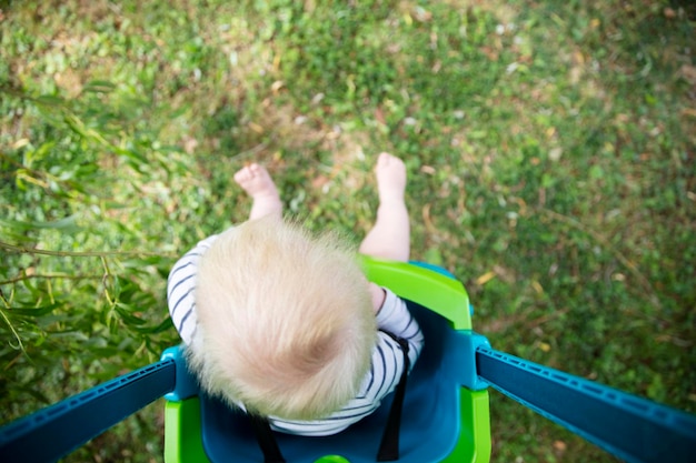 Mały chłopiec bawi się bawiąc się na huśtawce pod drzewem w ogrodzie