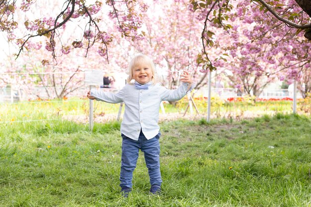 Mały chłopiec bawi się w kwitnącym ogrodzie sakura