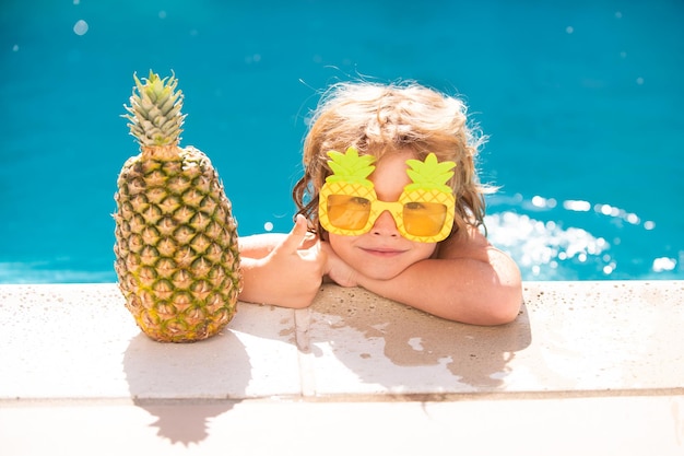 Mały chłopiec bawi się w odkrytym basenie w niebieskiej wodzie na letnie wakacje na tropikalnej plaży dziecko