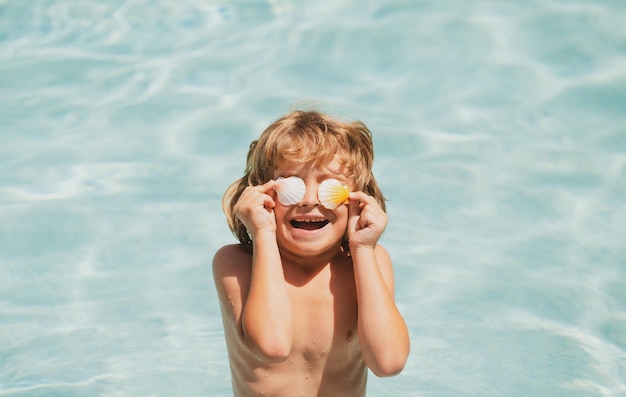 Mały chłopiec bawi się w odkrytym basenie w niebieskiej wodzie na letnie wakacje na tropikalnej plaży Dziecko