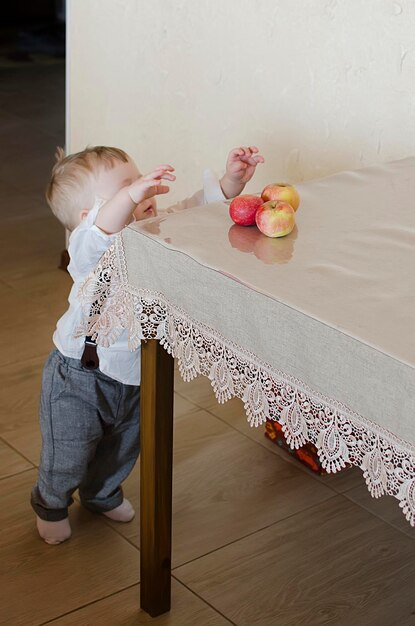 Mały chłopiec chce ukraść jabłko ze stołu