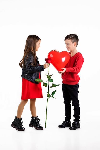 Mały chłopiec dający czerwoną różę dziewczynce