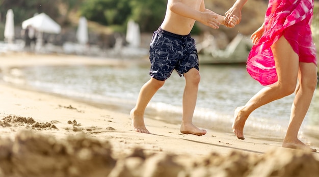 Mały chłopiec dziecko i młoda kobieta razem działa obok plaży piasek morze trzymając się za ręce, niewyraźne tło, koncepcja podróży, miejsce