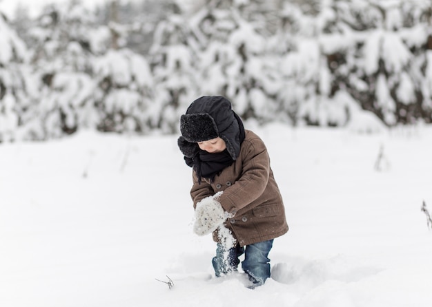 mały chłopiec gra śnieżkami w zimie w przyrodzie