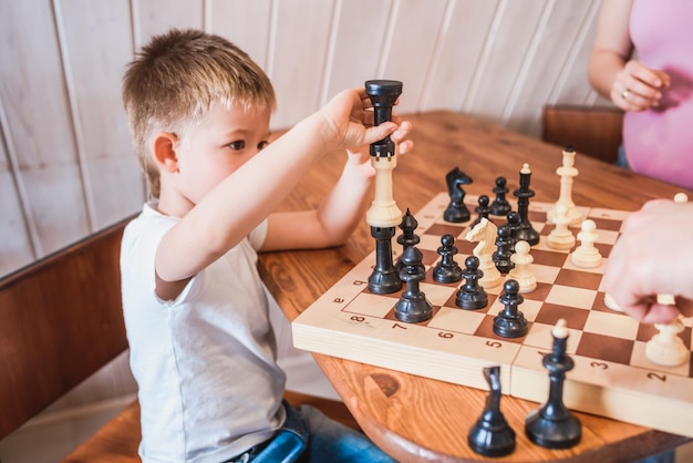 Mały chłopiec gra w szachy w domu przy stole