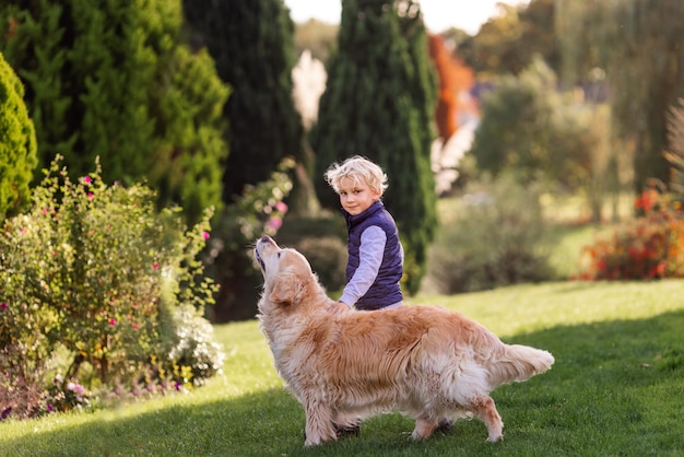 Mały Chłopiec Gry I Szkolenia Psa Golden Retriever W Polu W Letni Dzień Razem Cute Dziecko Z Portretem Doggy Domowych W Przyrodzie