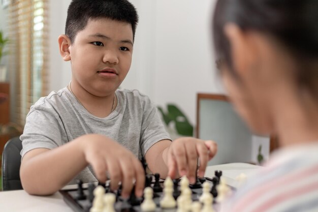 Mały chłopiec i mała dziewczynka grają w szachy w domuDzieci grają w szachy