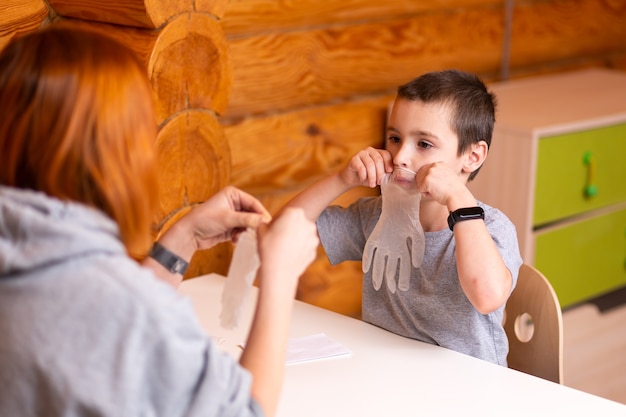 Mały Chłopiec I Mama Bawią Się, Pompują Jednorazowe Rękawiczki Chirurgiczne I Przygotowują Się Do Eksperymentów Chemicznych W Domu