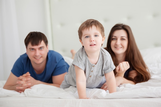 Mały chłopiec i rodzice na łóżku rodziców w piżamie
