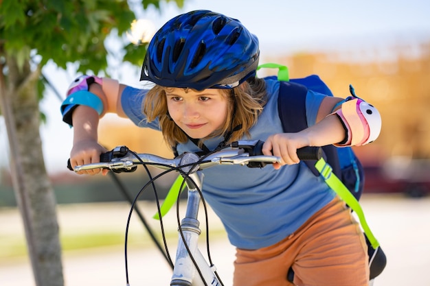 Mały chłopiec jeździ na rowerze w letnim parku. Dziecko jeździ rowerem na podjeździe na zewnątrz.