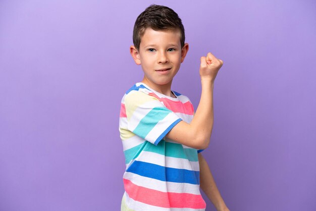 Zdjęcie mały chłopiec na fioletowym tle robi silny gest