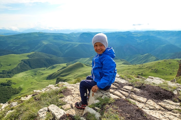 Mały chłopiec na klifie płaskowyżu na tle góry Elbrus Bermamyt