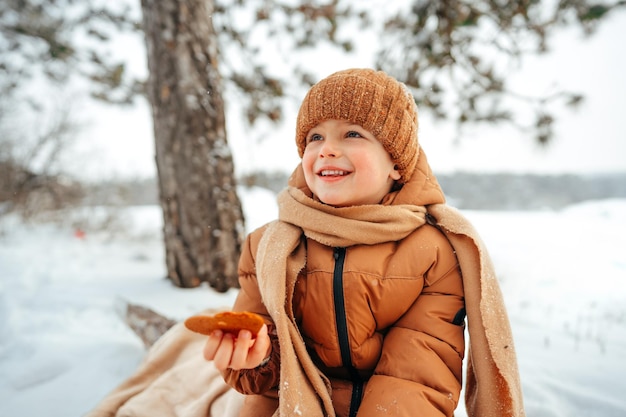 Mały chłopiec na pikniku w zimowym lesie