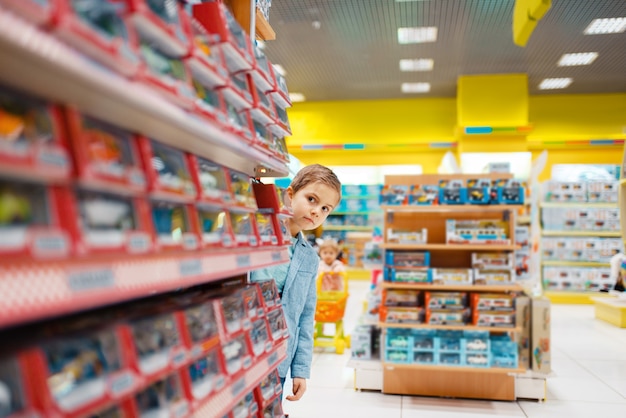 Mały chłopiec na półce w sklepie dla dzieci. Syn wybiera zabawki w supermarkecie