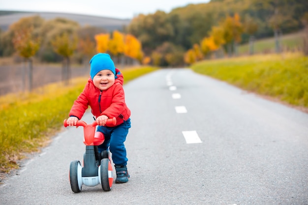 Mały chłopiec na rowerze lub wykidajło na zewnątrz lub ścieżka rowerowa, wyglądający na szczęśliwego