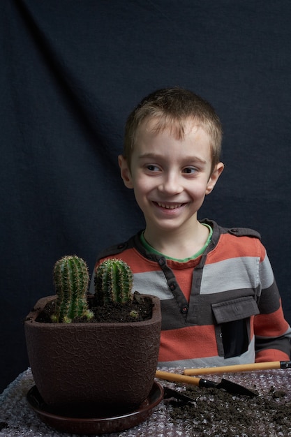 Zdjęcie mały chłopiec odłożył kaktusa z rośliny doniczkowej