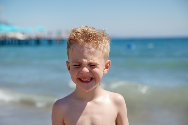 mały chłopiec płacze na plaży nad brzegiem morza jest zdenerwowany Koncepcja letniego wypoczynku