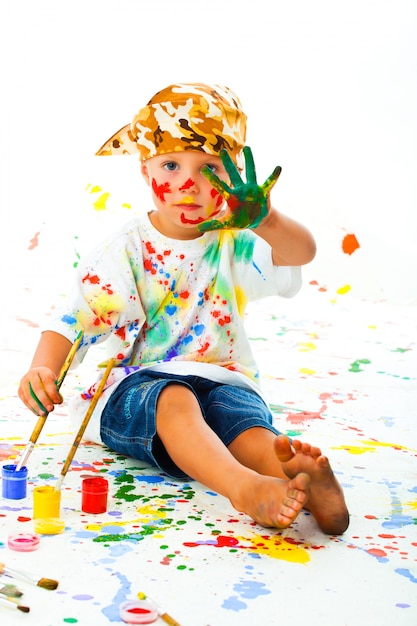 Zdjęcie mały chłopiec poplamiony farbą rysuje