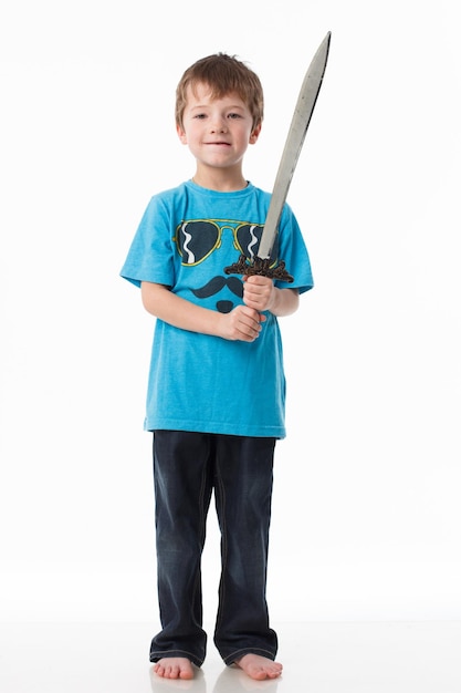 Mały chłopiec pozuje z mieczem w studio na szarym tle