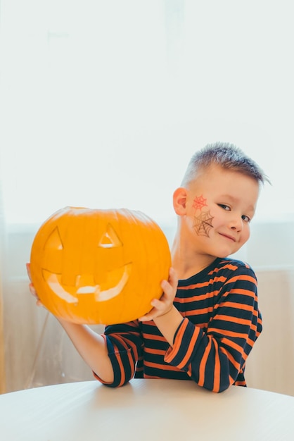 Mały chłopiec robi głowę z dyni halloween w domu