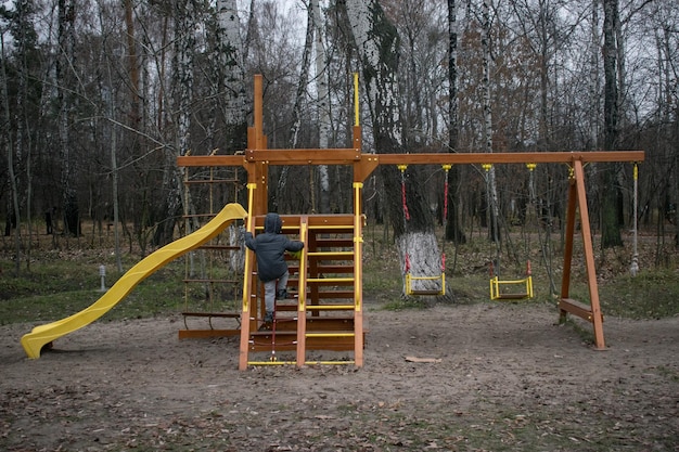 Mały chłopiec sam na placu zabaw jesienią