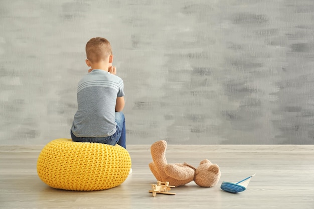 Mały chłopiec siedzi blisko ściany w pustym pokoju Koncepcja autyzmu