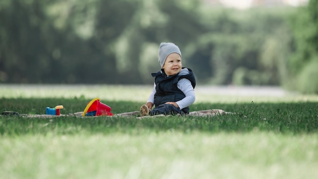 Mały chłopiec siedzi na trawniku w wiosenny dzień