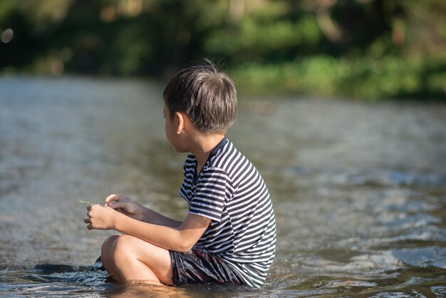Mały chłopiec siedzi razem w kanale rzeki