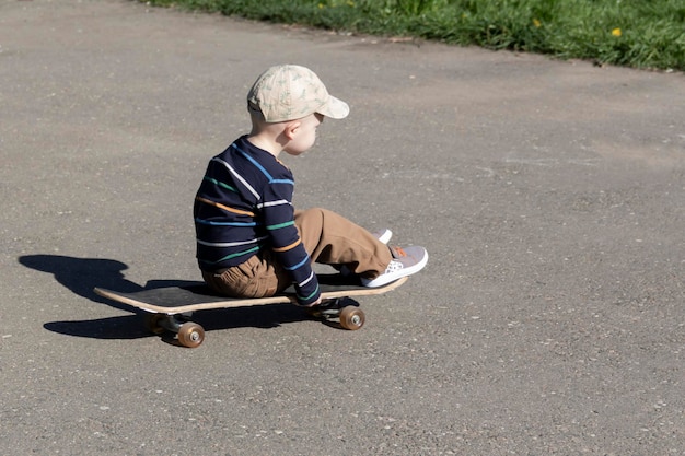Mały chłopiec uczy się jazdy na deskorolce sportów ekstremalnych latem na placu zabaw w parku i na świeżym powietrzu