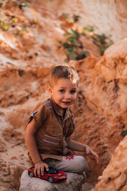 Mały chłopiec usiadł na skale wśród piasku